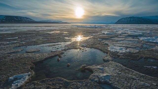 Tranquil Arctic Landscape with Sun Over Ice Floes and Meltwater