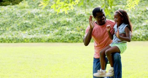 Father Lifting Daughter in Joyful Park Scene