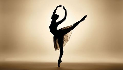 Ballet dancer silhouette performing arabesque on pointe with backlit tulle skirt