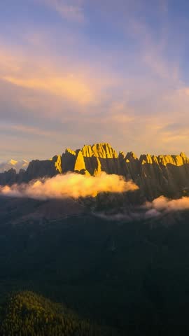 Vertical Sunrise Light Pouring Over Jagged Mountain Ridge with Drifting Clouds