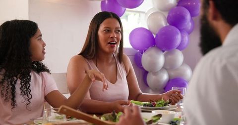 Family Celebrating at Home Eating Meal Together with Balloons