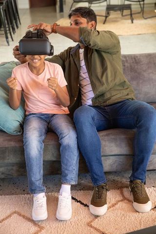 Father adjusting vr headset for excited son at home