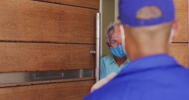 Delivery Worker Wearing Uniform and Mask Bringing Package to Elderly Man - Download Free Stock Images Pikwizard.com