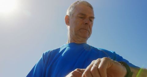 Senior Man on Promenade Checks Smartwatch in Sunlight
