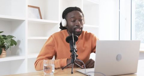 African American man recording podcast at home studio with laptop, microphone, headphones