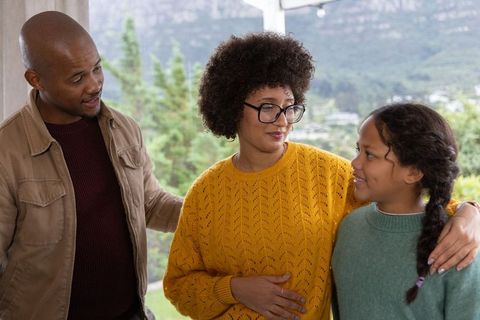 Diverse family sharing warm moment on balcony, parents comforting daughter in cozy sweaters