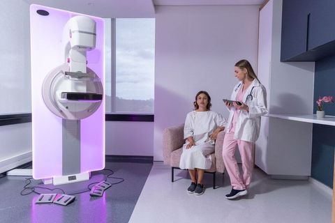 Diverse woman undergoing mammography consultation with radiology tech in pink scrubs