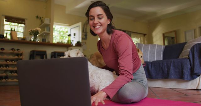 Caucasian woman exercising with her pet dog using laptop at home. lifestyle, fitness, pet, companionship and animal friendship concept.