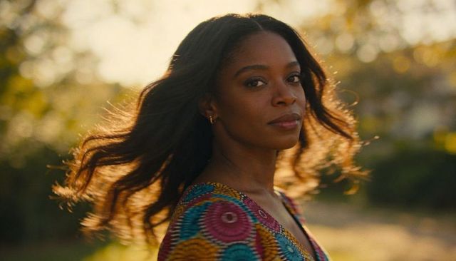 Sunlit woman turning toward viewer with flowing hair and vibrant patterned dress
