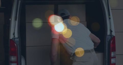 Nighttime delivery process concept with male courier loading boxes