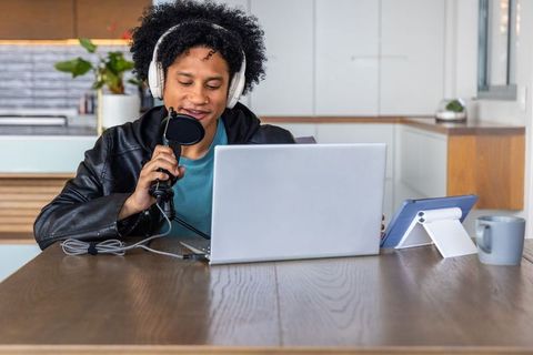 African american man recording podcast in modern kitchen with laptop headset and pop filter
