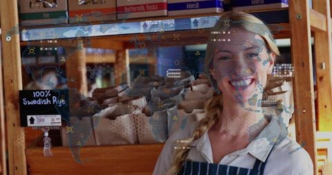 Cheerful clerk at artisanal bakery with digital world map overlay