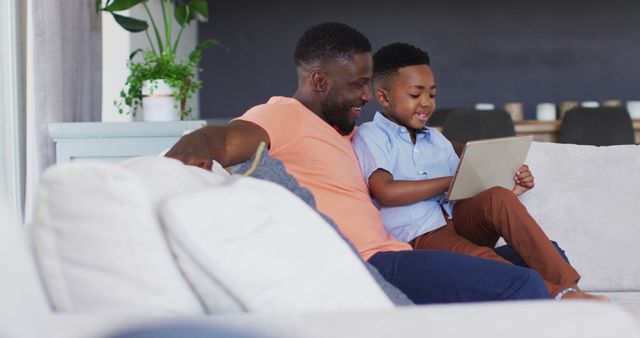 Smiling African American Father and Son Using Digital Tablet on Couch - Download Free Stock Images Pikwizard.com