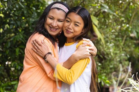 Mother and daughter sharing heartfelt hug in lush backyard