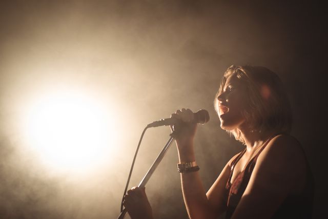Confident female singer performing in illuminated nightclub - Download Free Stock Photos Pikwizard.com