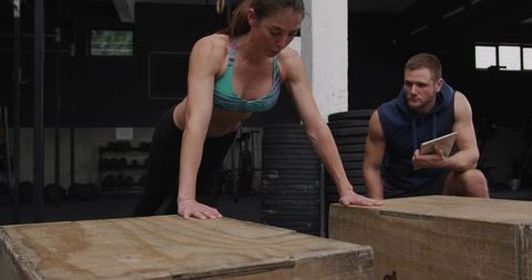 Athletic Woman Performing Raised Push-Ups with Coach Observation