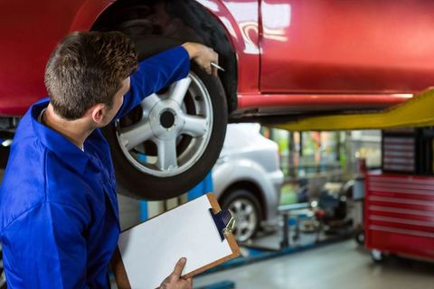 Skilled Mechanic Examining Car Wheel in Modern Garage