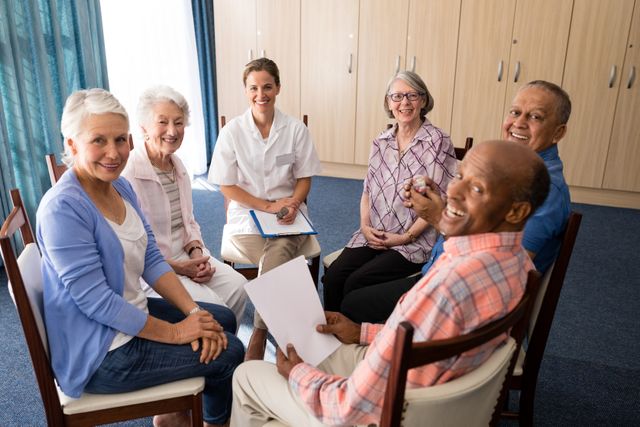 This image depicts a group of happy seniors sitting in a circle with a female doctor, suggesting a group therapy or support session at a retirement home. Ideal for use in healthcare, senior living, and community support materials, it highlights the importance of social interaction and professional care in elderly wellness.