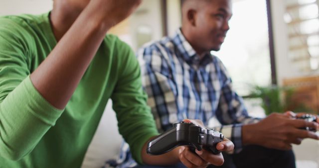 Two african american brothers sitting on a couch and playing image games. healthy outdoor family leisure time together.