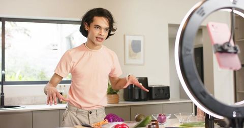 Young creator filming cooking tutorial with ring light and smartphone in modern kitchen