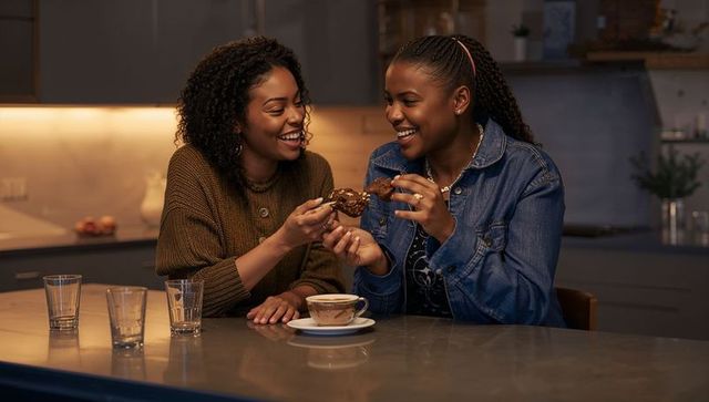 Friends sharing chocolate pastry and coffee while laughing at cozy modern kitchen island