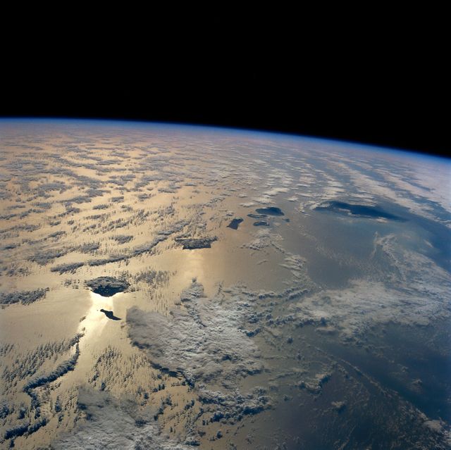 A stunning aerial view showing the Hawaiian Islands from space with a clear view of the Earth's horizon. Ideal for use in projects related to travel, tourism, nature, geography, environmental studies, and educational materials. This image highlights the beauty of the Hawaiian Archipelago, its clouds, and surrounding ocean, evoking themes of adventure and exploration.