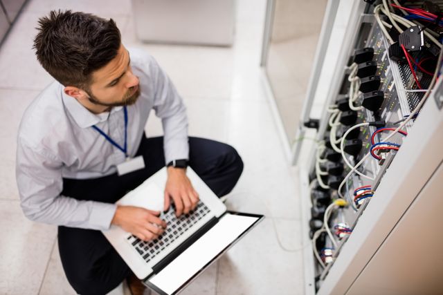 Technician using laptop while analyzing server in server room