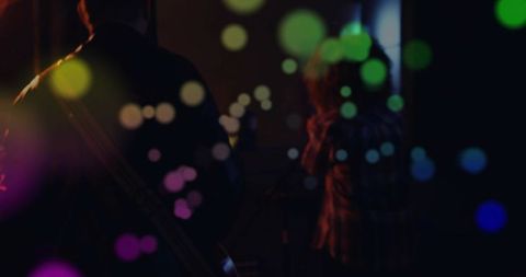 Shadowed musical duo performing on intimate stage with colorful bokeh lights