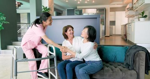 Smiling Senior Women with Caring Nurse Assisting in Modern Living Room