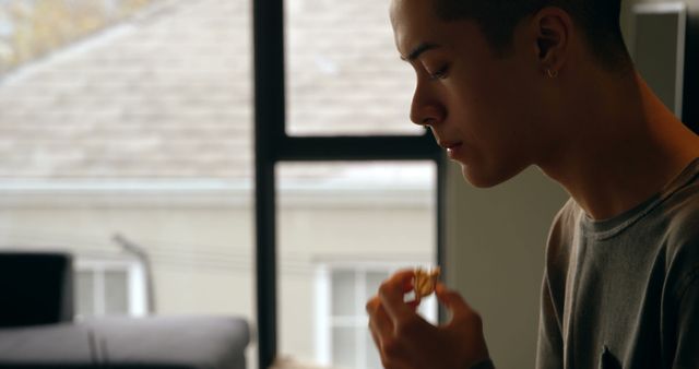 Pensive Young Man Enjoying Snack by Window in Cozy Room - Download Free Stock Images Pikwizard.com