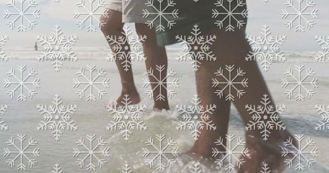 Father and Son Beach Stroll with Overlaying Snowflakes at Seashore