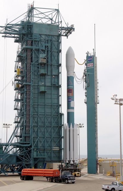 Showing the Delta II rocket carrying the Gravity Probe B spacecraft on the launch pad at Vandenberg Air Force Base. The scene includes the Mobile Service Tower and other infrastructure, providing an authentic look at the intricate preparations involved in space missions. This image can be used for articles and content related to NASA missions, space technology, engineering processes, and educational materials about space exploration.