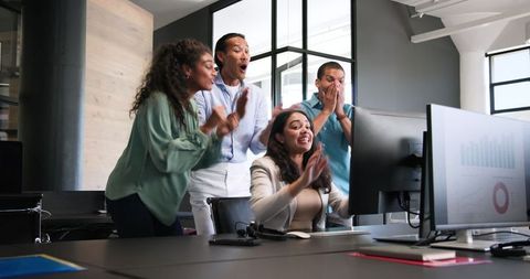 Diverse team celebrating success in modern office workspace