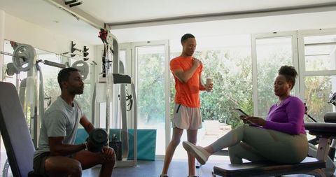 Motivated Couple Exercising with Weights and Tablet in Home Gym