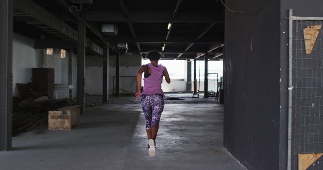 African american woman wearing sports clothing jogging through an empty urban building. urban fitness and healthy lifestyle.