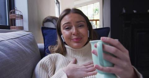 Young Woman Relaxing on Couch with Coffee and Earbuds - Download Free Stock Images Pikwizard.com