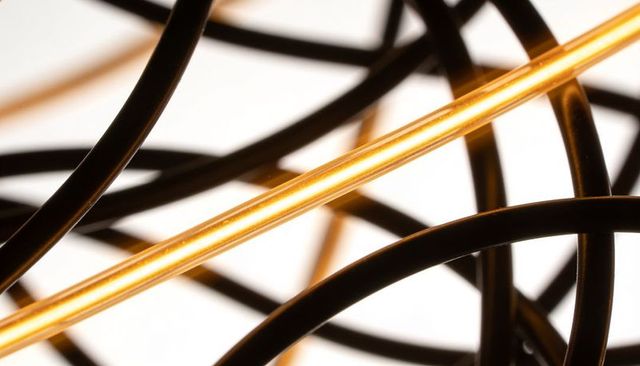 Tangled black cords with sleek gold rod, abstract geometric luxury background