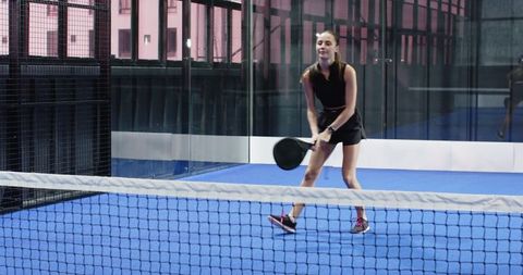 Woman engaging in padel sport activity on modern blue court
