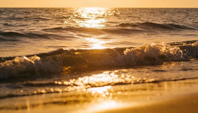 Golden hour waves glinting on wet sand at shoreline, sunset ocean reflections