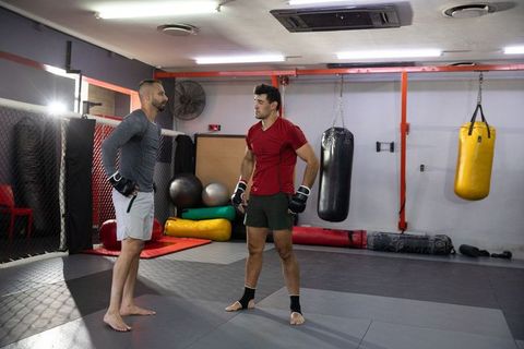 Boxing coach guiding mma trainee during sparring session in modern gym training facility