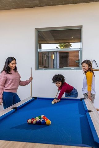Diverse women playing pool in modern home game room enjoying casual social recreation