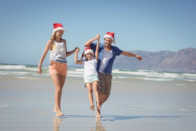 Family wearing Santa hats enjoying a sunny day at the beach. Perfect for holiday-themed promotions, travel advertisements, and festive greeting cards. Highlights joy, togetherness, and the festive spirit in a summer setting.