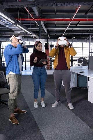 Coworkers testing virtual reality headsets in modern open office for team collaboration