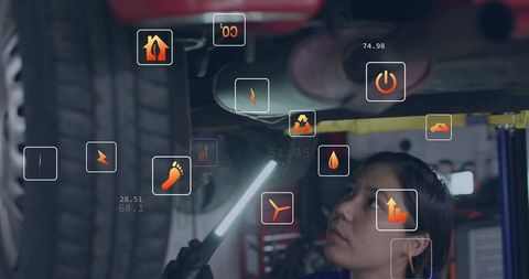 Female mechanic inspecting undercarriage with led light and augmented reality diagnostics in garage