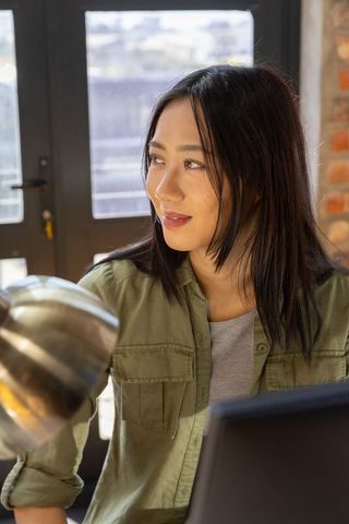 Thoughtful Woman in Modern Office Space with Laptop
