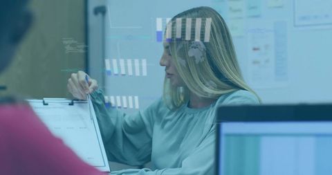 Businesswoman presenting data with pen over augmented charts in collaborative meeting room