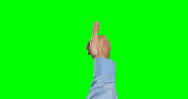 A Caucasian hand is giving a thumbs up against a green screen background, with copy space. It suggests approval or a positive response in a setting that allows for easy graphic editing or compositing.