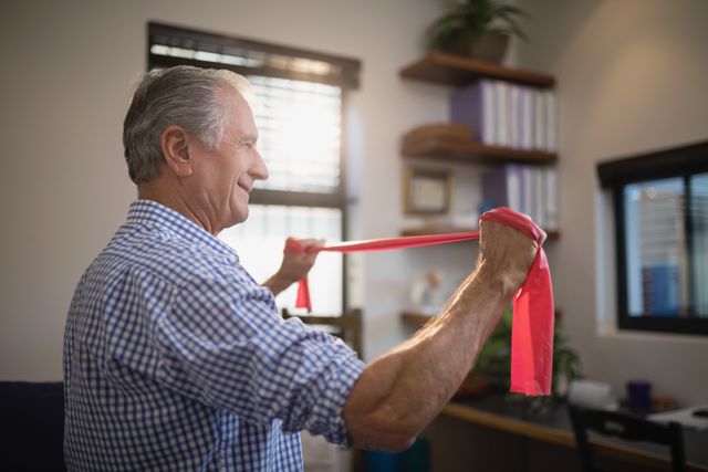 Side view of senior man pulling resistance band while standing in hospital ward