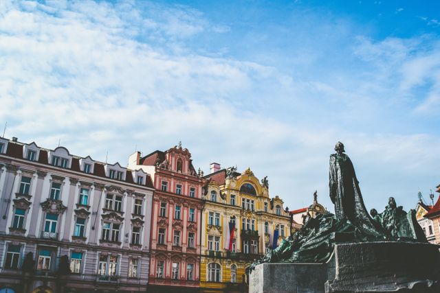 Colorful historic buildings and a prominent statue under a clear blue sky. Suitable for travel blogs, tourism websites, and cultural heritage promotions. Ideal for illustrating historic European cities and urban landscapes.