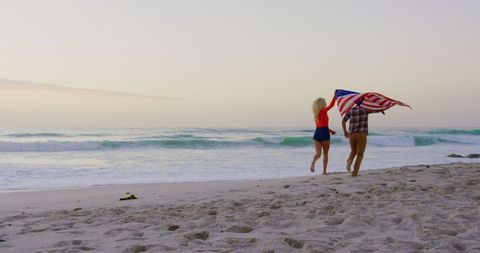 Young Couple Celebrating with American Flag on Beach